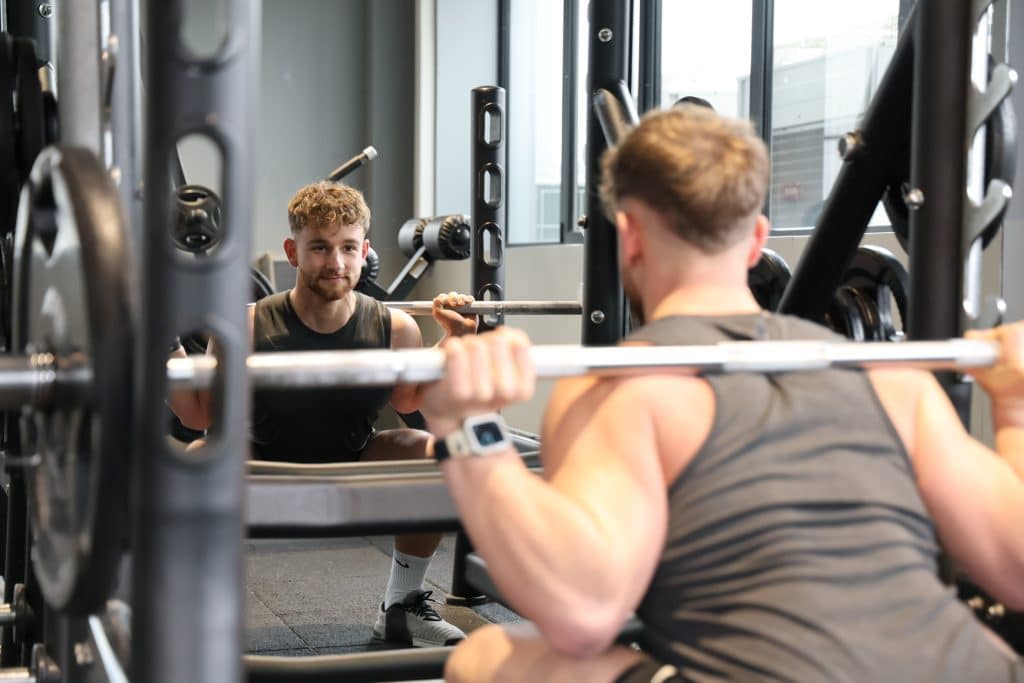 Un homme en train de faire un squat à la barre